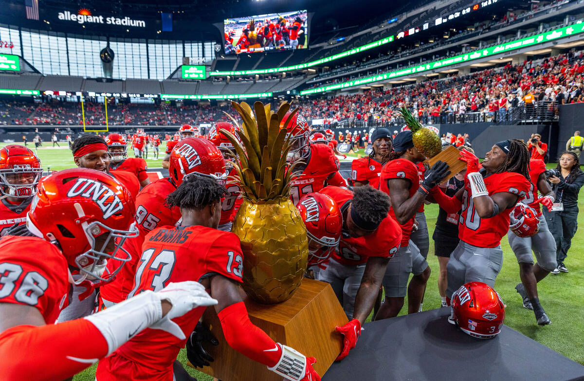 UNLV players swarm about the trophies after defeating Hawaii in the Ninth Island Showdown follo ...