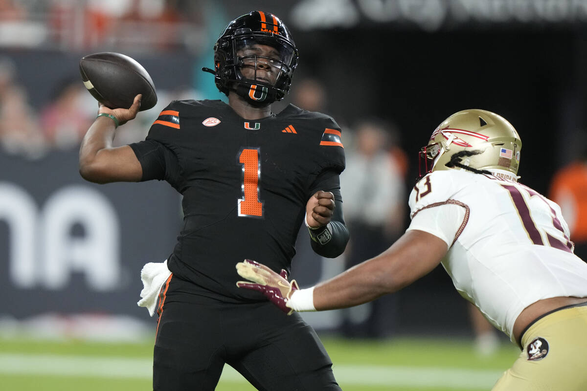 Miami quarterback Cam Ward (1) looks to pass as Florida State defensive lineman Sione Lolohea ( ...