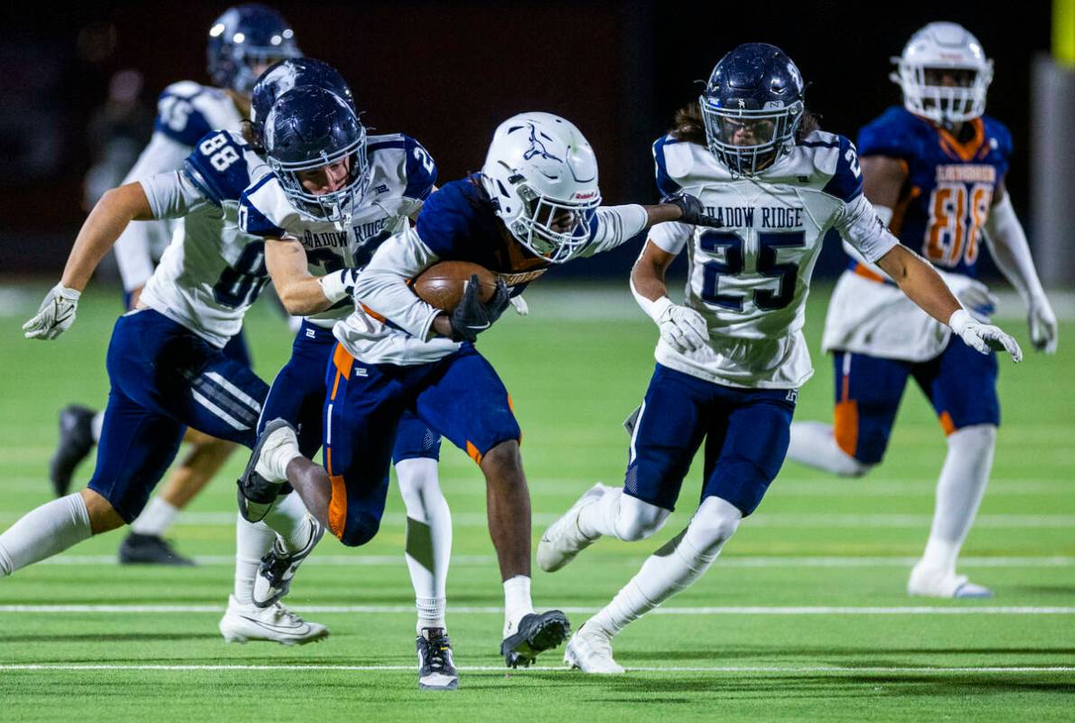 Legacy halfback Zaione Henderson (5) is grabbed from behind by Shadow Ridge safety Hawkin Ledin ...