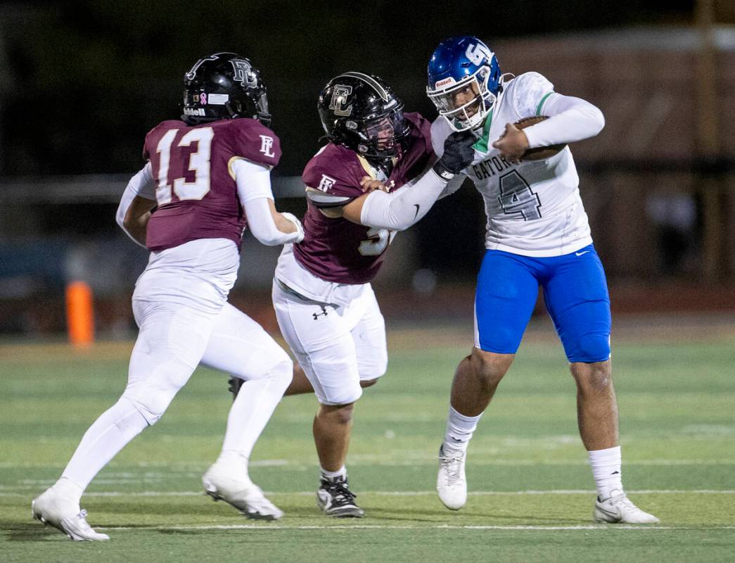 Green Valley quarterback Ben Parker (4) is sacked by Faith Lutheran sophomore Joel Sandoval, le ...