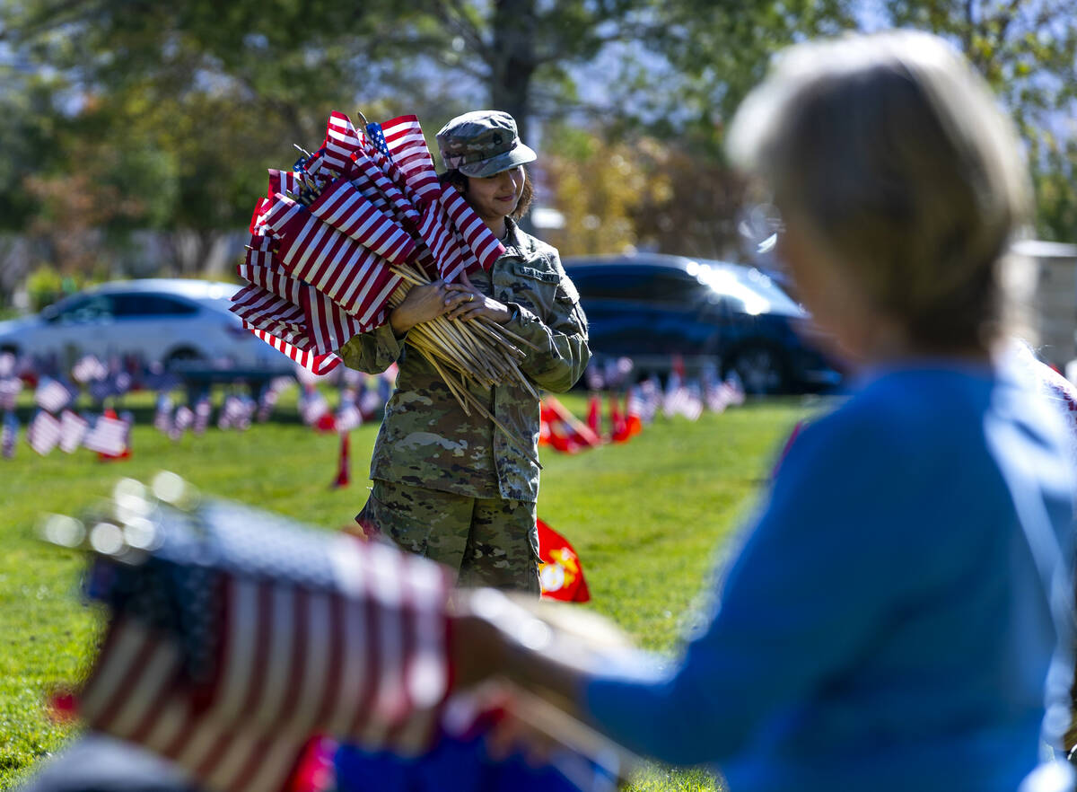 SSgt. Jessica Moreno holds a large bunch of American flags as she and other volunteers place ar ...