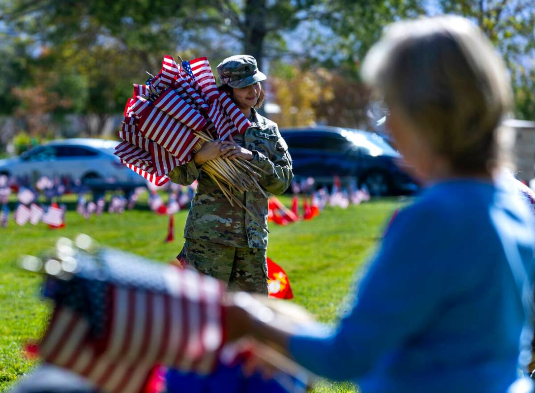 SSgt. Jessica Moreno holds a large bunch of American flags as she and other volunteers place ar ...