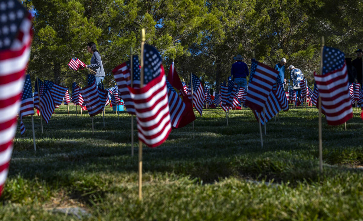 Volunteers place around 14,000 small American flags at veterans grave markers in the Southern N ...