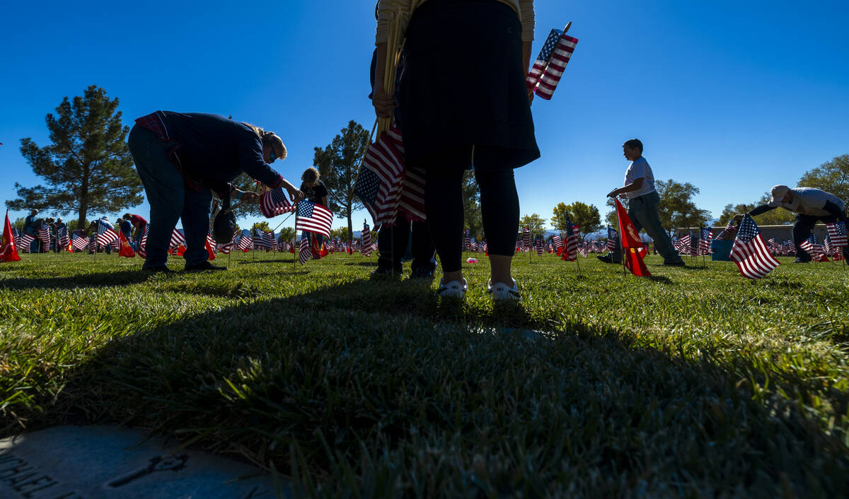 Volunteers place around 14,000 small American flags at veterans grave markers in the Southern N ...