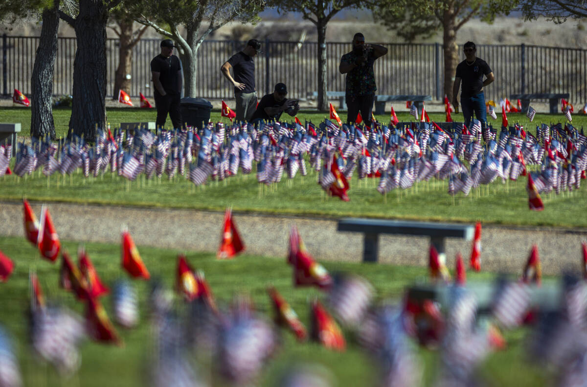 Visitors take in some of around 14,000 small American flags at veterans grave markers in the So ...