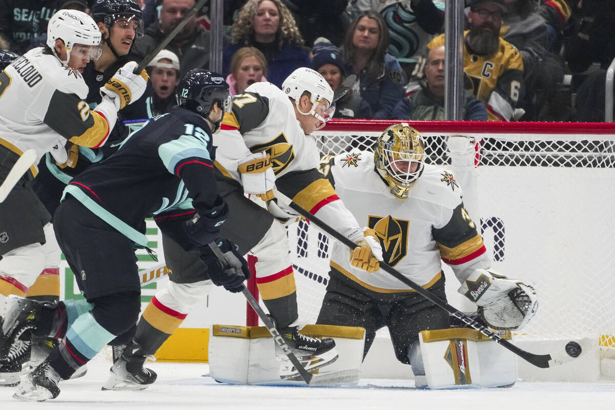 Vegas Golden Knights defenseman Ben Hutton, second from right, reaches out to make a save as go ...