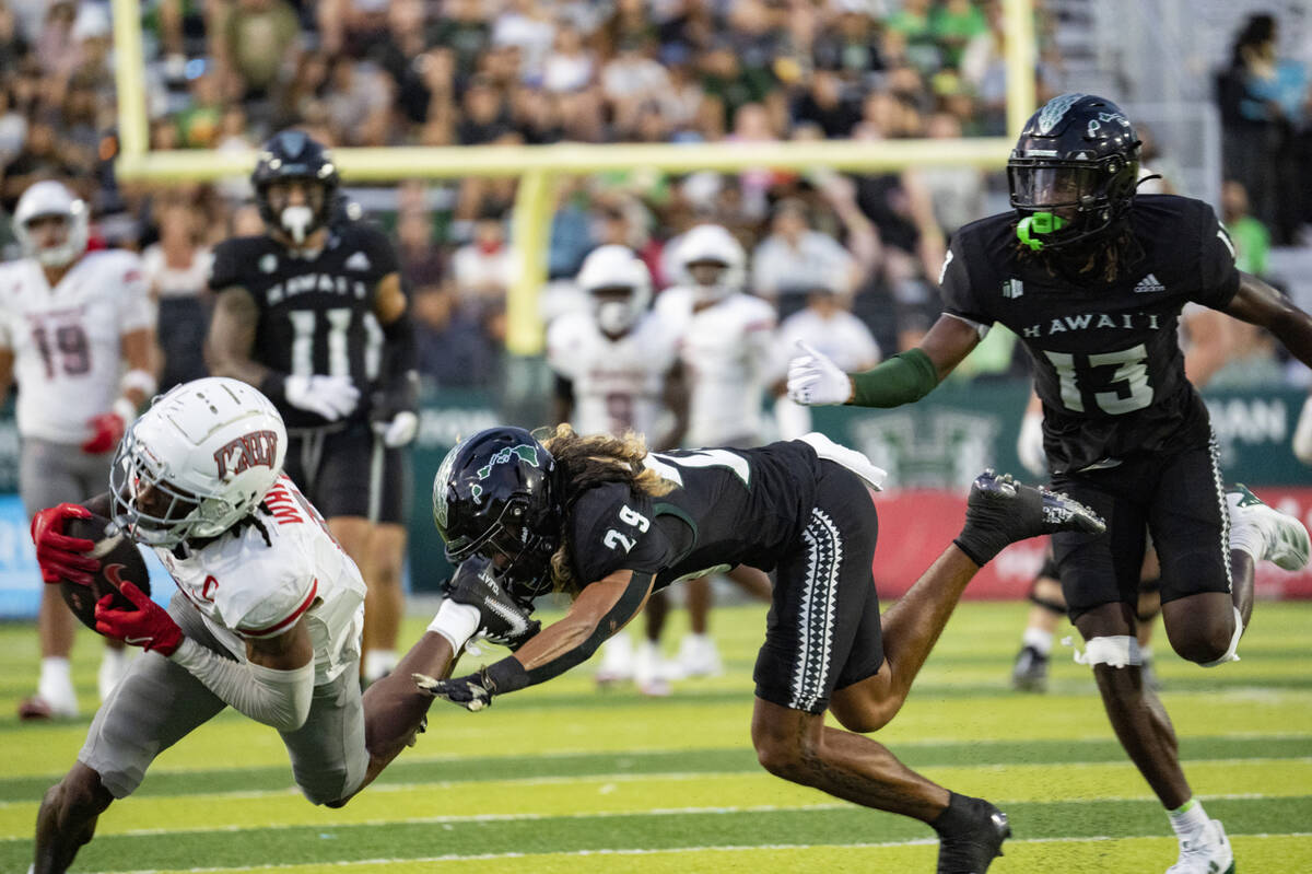 UNLV wide receiver Ricky White III, left, gets defended by Hawaii defensive back Kilinahe Mendi ...