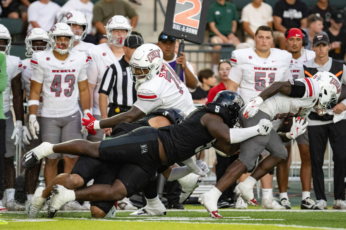 Hawaii defensive lineman Tariq Jones (5) grabs UNLV running back Jai'Den Thomas (9) during the ...