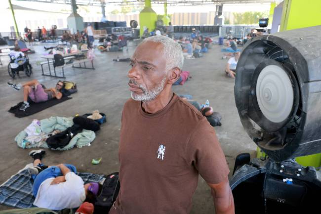 David West, 59, talks to a reporter in a cool mist at the Courtyard Homeless Resource Center in ...