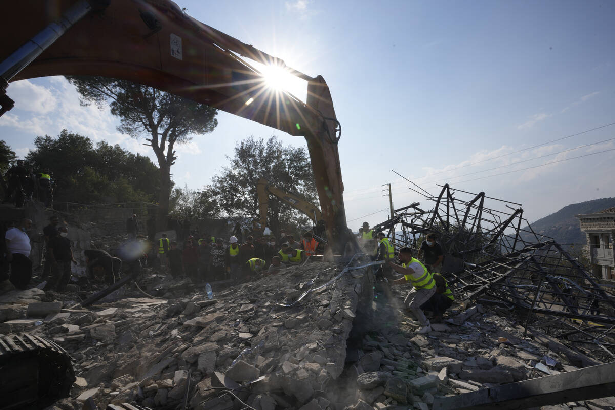 Rescue workers use an excavator to remove the rubble of a destroyed house hit in an Israeli air ...