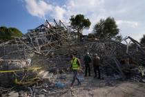 People and a rescue worker gather at the site where an Israeli airstrike hit a house in Aalmat ...