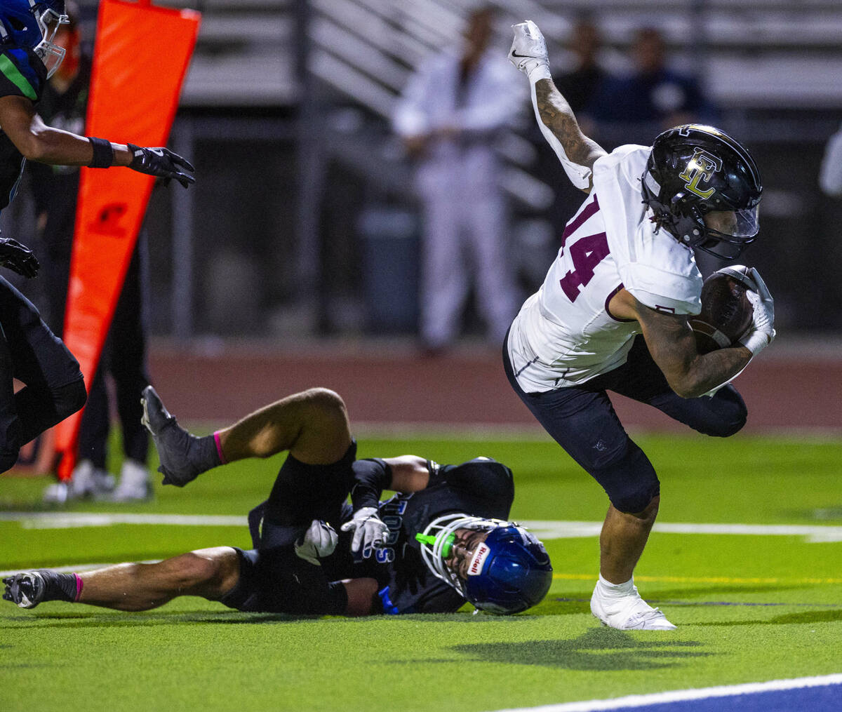 Faith Lutheran running back Cale Breslin (14) takes a Green Valley hit and still scores during ...