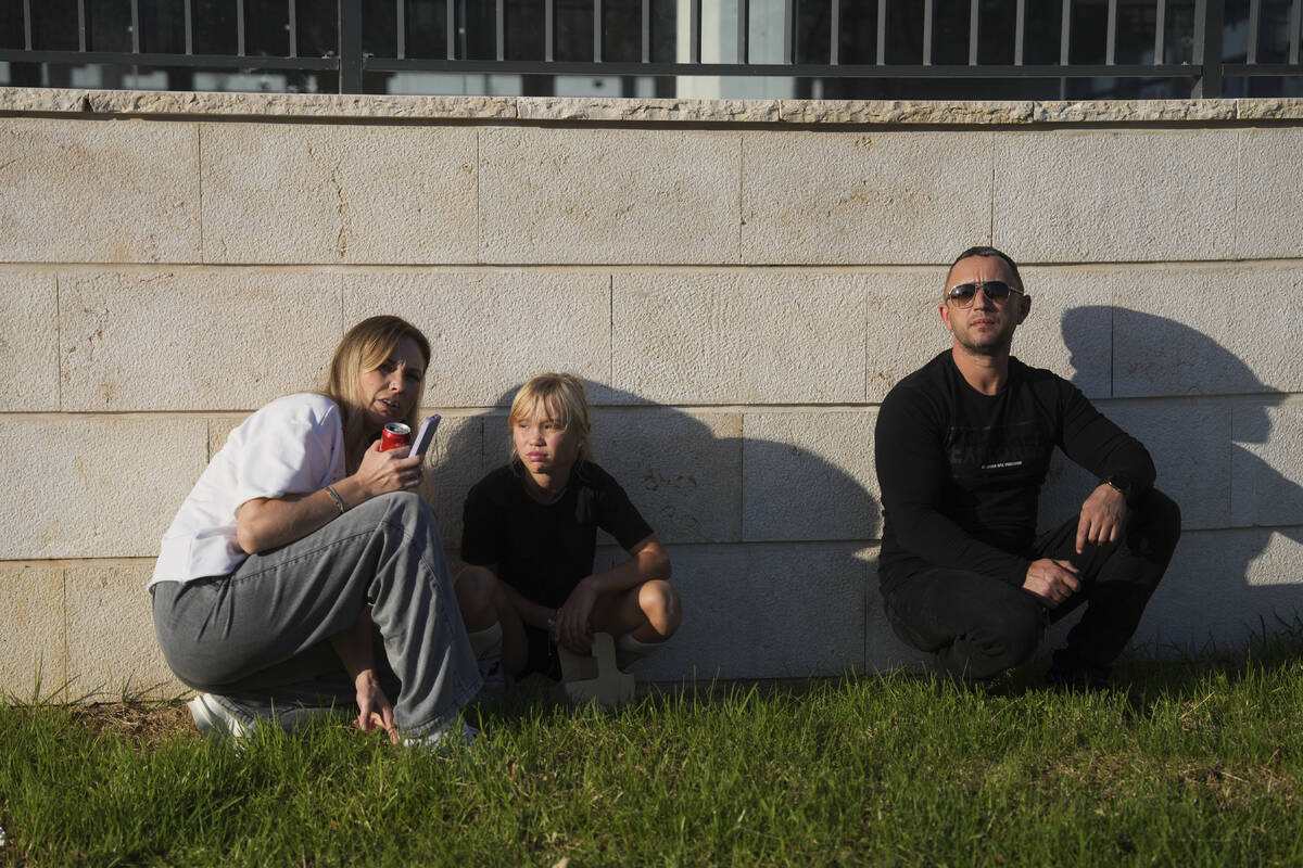 People take cover as a siren sounds a warning of incoming rockets fired from Lebanon, in Kiryat ...