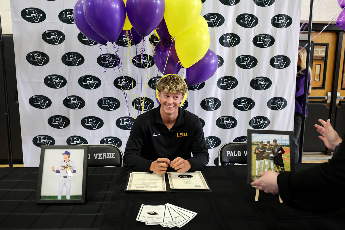 Palo Verde baseball player Ethan Clauss smiles as a family member sets up props before he signs ...