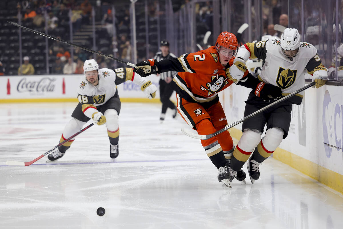 Anaheim Ducks defenseman Jackson LaCombe, center, and Vegas Golden Knights right wing Keegan Ko ...