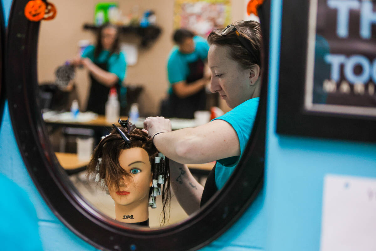 Students practice perms on mannequins during a cosmetology class at Florence McClure Women&#x20 ...