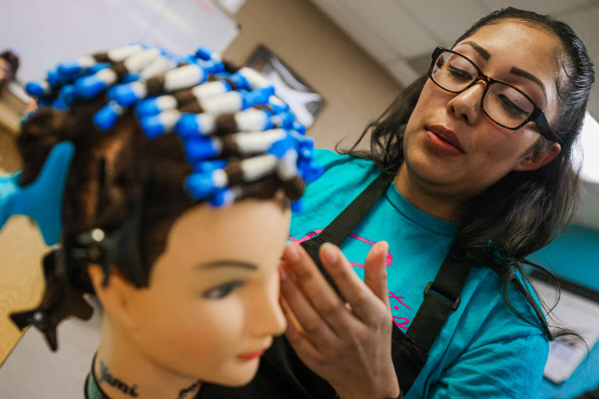 Brenda Garcia practices a perm on a mannequin during a cosmetology class at Florence McClure Wo ...