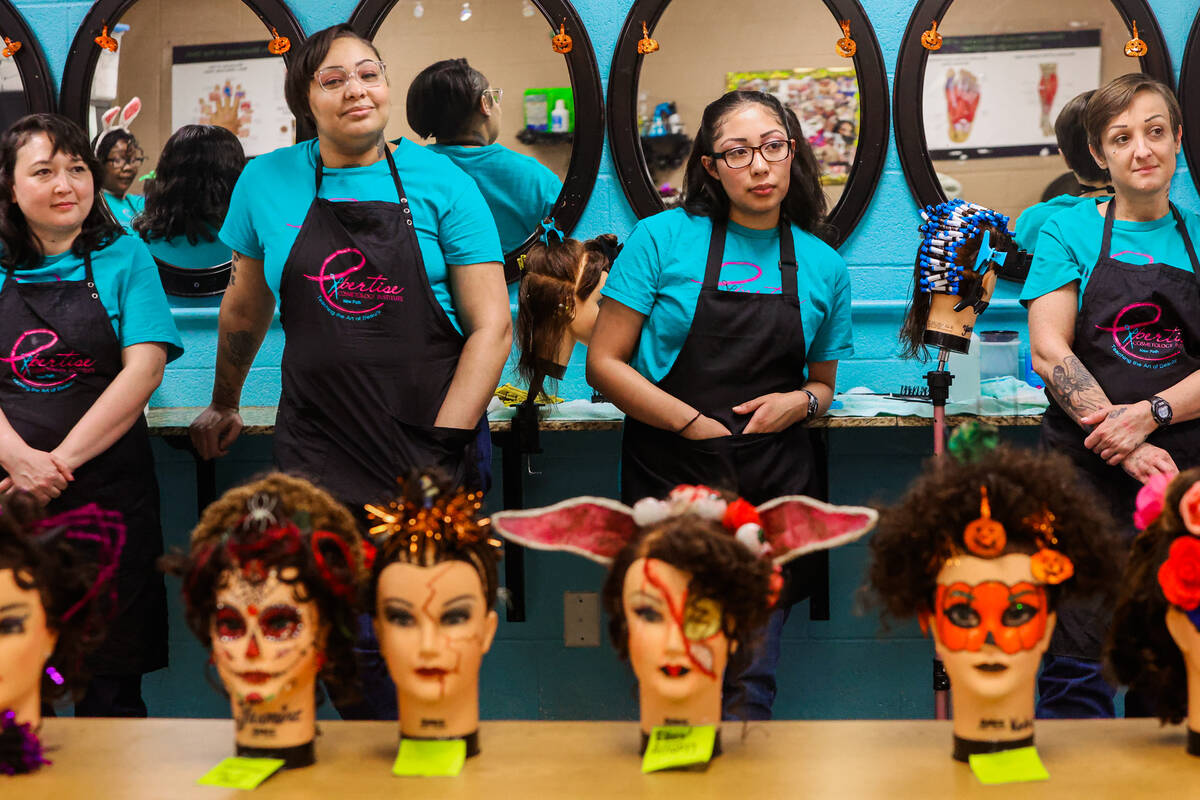 Inmates who are studying for their cosmetology licenses stand in front of mannequins that they ...