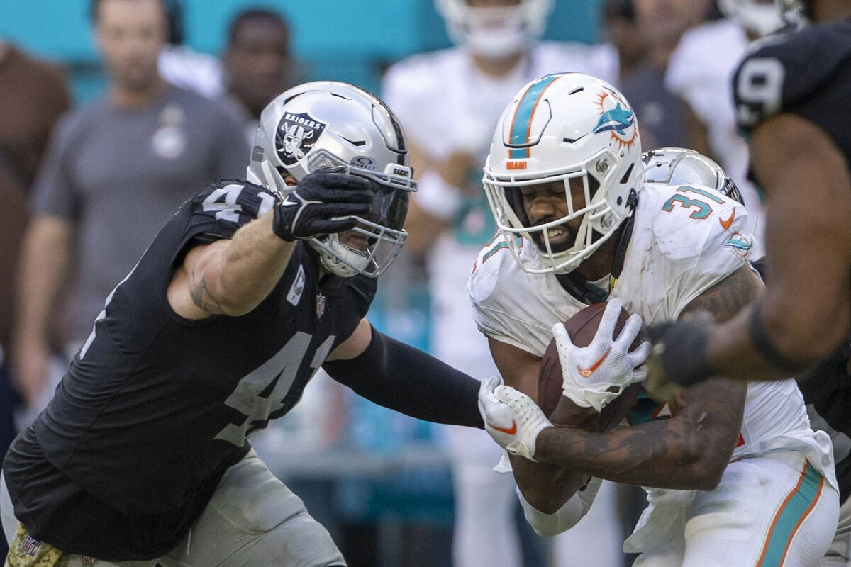 Raiders linebacker Robert Spillane (41) tackles Miami Dolphins running back Raheem Mostert (31) ...