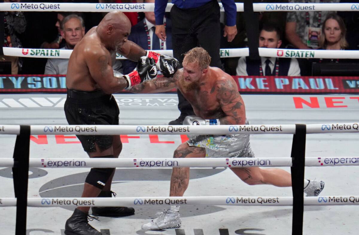 Jake Paul hits Mike Tyson during their heavyweight boxing match, Friday, Nov. 15, 2024, in Arli ...