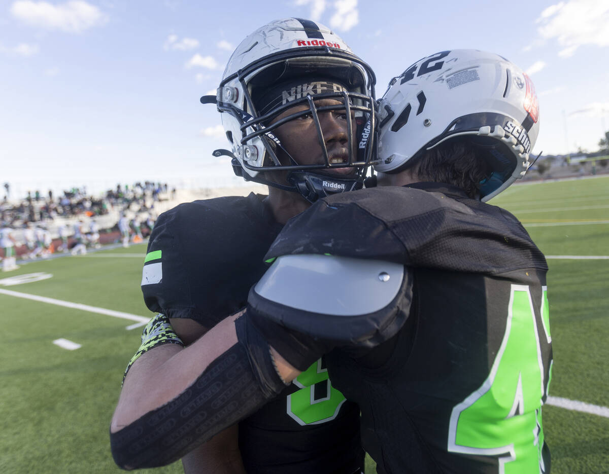 SLAM Academy sophomore Dereon Johnson, left, is hugged by linebacker Kyler Proudfoot, right, af ...