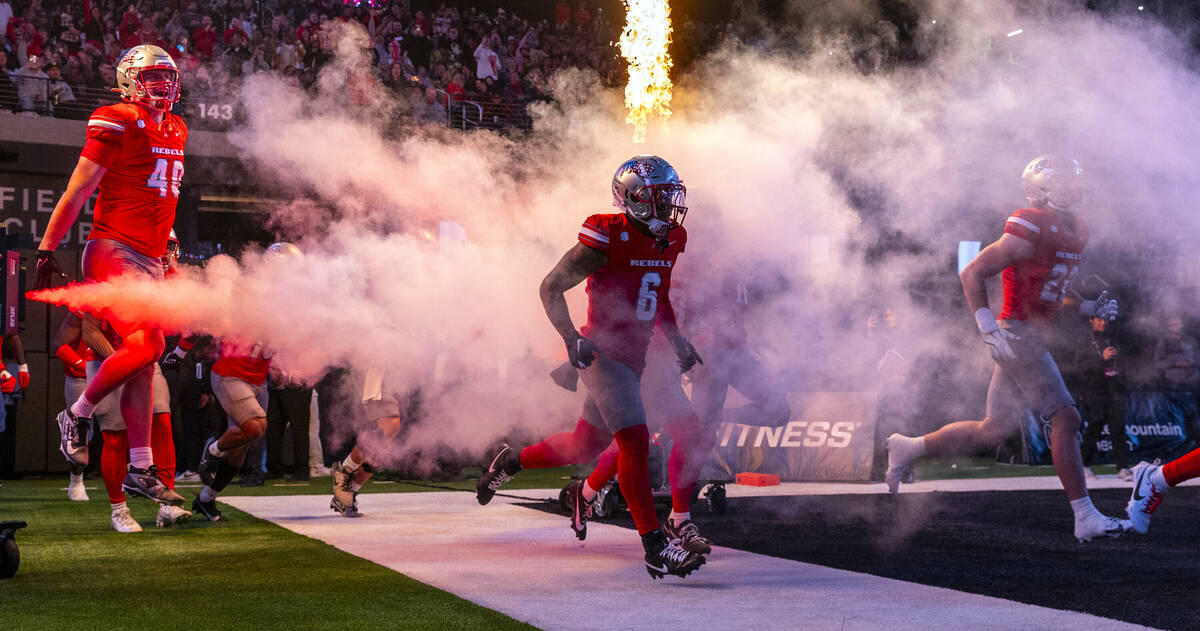 UNLV players take the field through fog as they ready to face the San Diego State Aztecs during ...