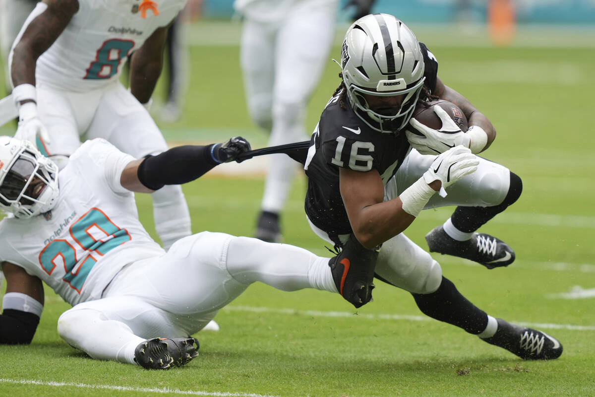 Miami Dolphins linebacker Jordyn Brooks (20) holds onto Las Vegas Raiders wide receiver Jakobi ...