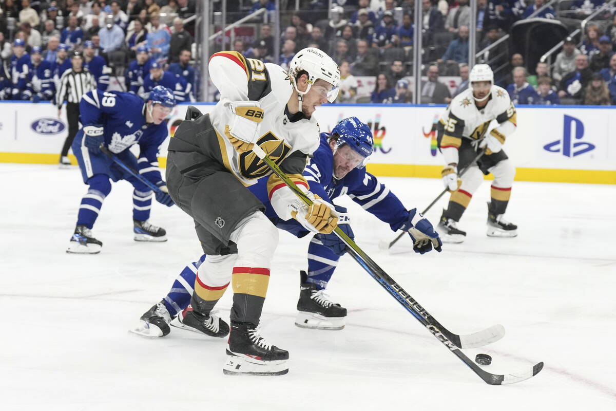 Vegas Golden Knights' Brett Howden (21) and Toronto Maple Leafs' Morgan Rielly (44) battle for ...