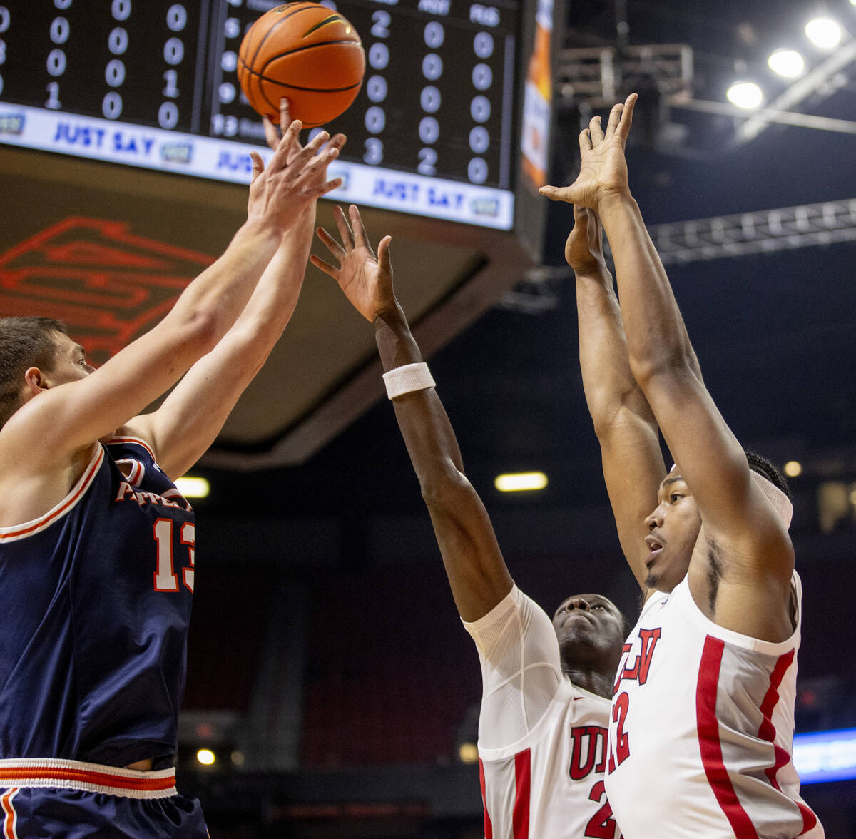 UNLV forward Pape N'Diaye, center, and forward Jacob Bannarbie, right, attempt to block a shot ...