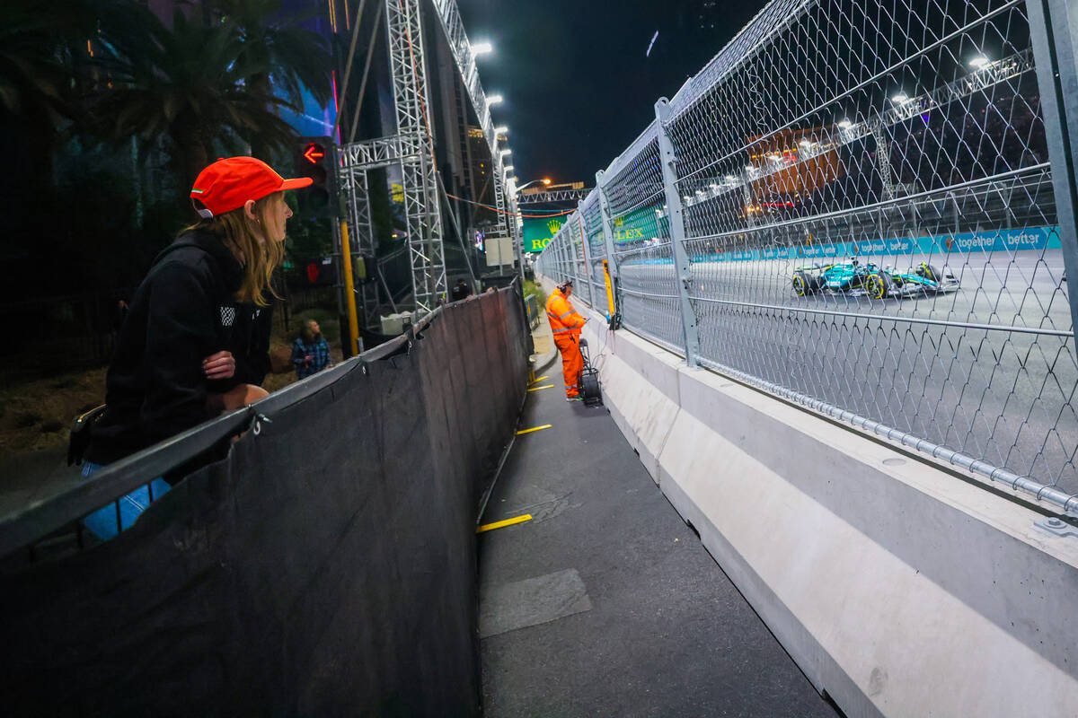 Formula 1 fan Maya Nypl of Paradise, Calif., is hoisted over a barrier to sneak a peek of drive ...