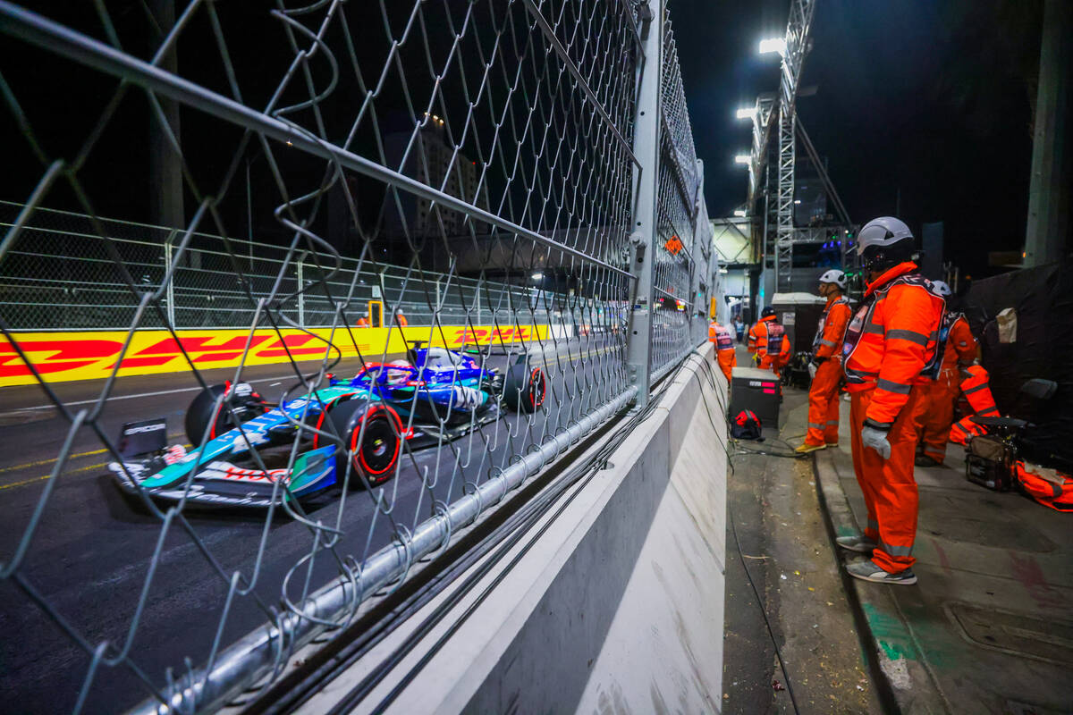 Formula 1 marshals watch drivers speed by as they work the circuit during the second practice s ...