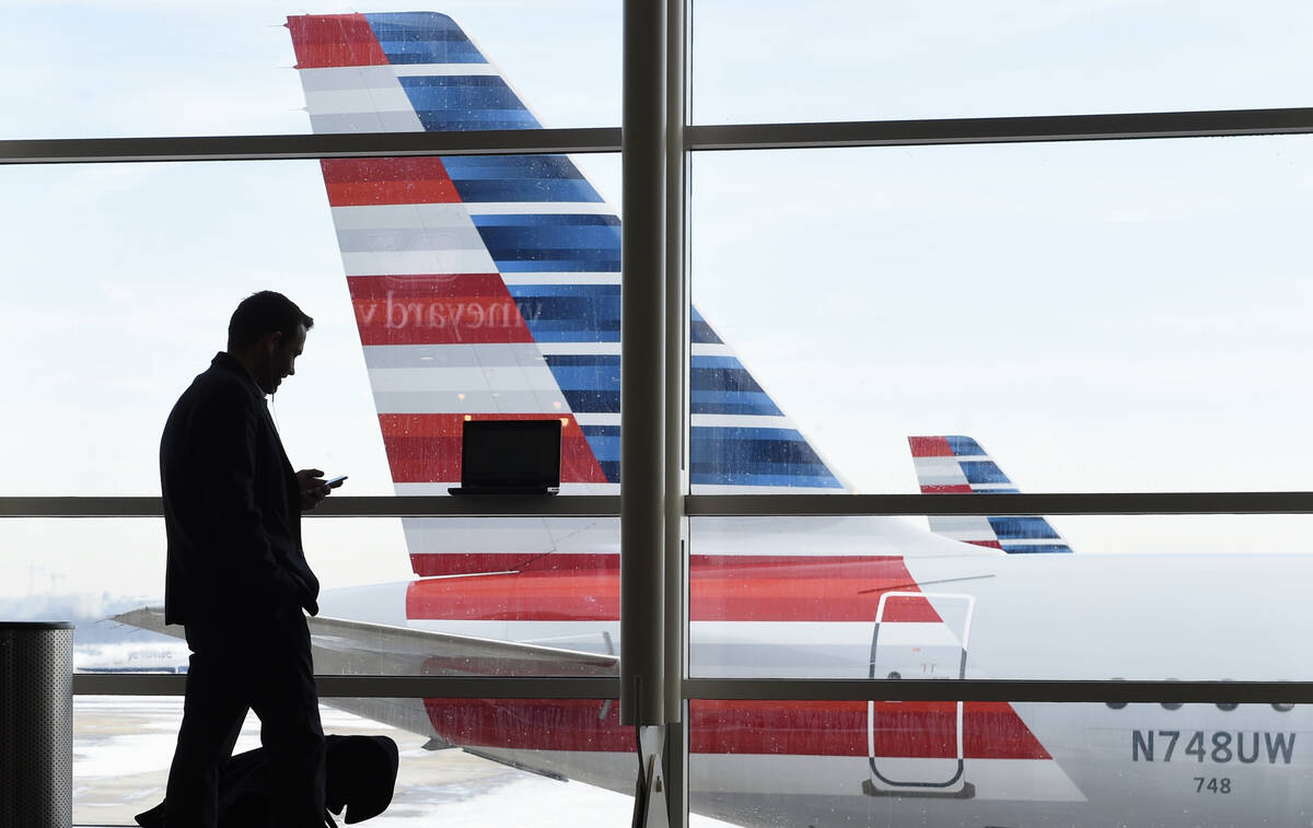 A passenger talks on the phone with American Airlines jets parked behind him at Washington's Ro ...