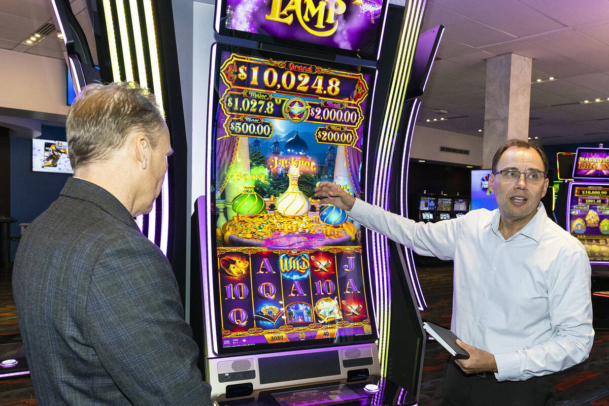 Nick Khin, right, a COO of Gaming for IGT, demonstrates how Mystery of the Lamp game is played ...