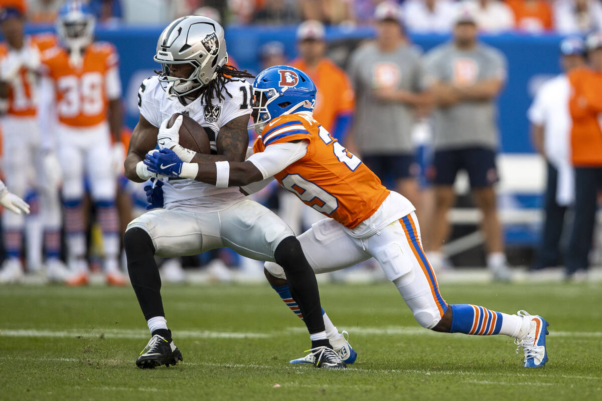 Raiders wide receiver Jakobi Meyers (16) makes a catch with Denver Broncos cornerback Ja'Quan M ...