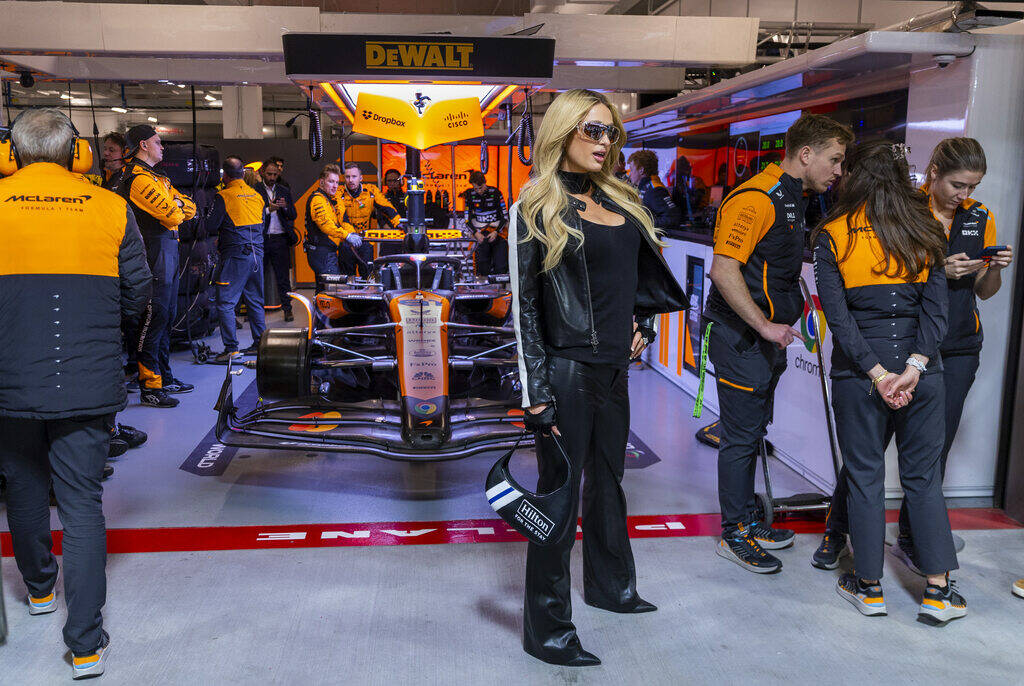 Celebrity Paris Hilton strikes a pose outside the McLaren garage before the start of the during ...