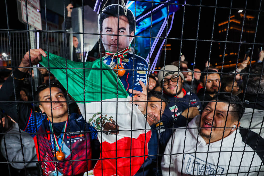 Fans show off a cardboard cutout of Red Bull rider Sergio Perez from behind a fence during the ...