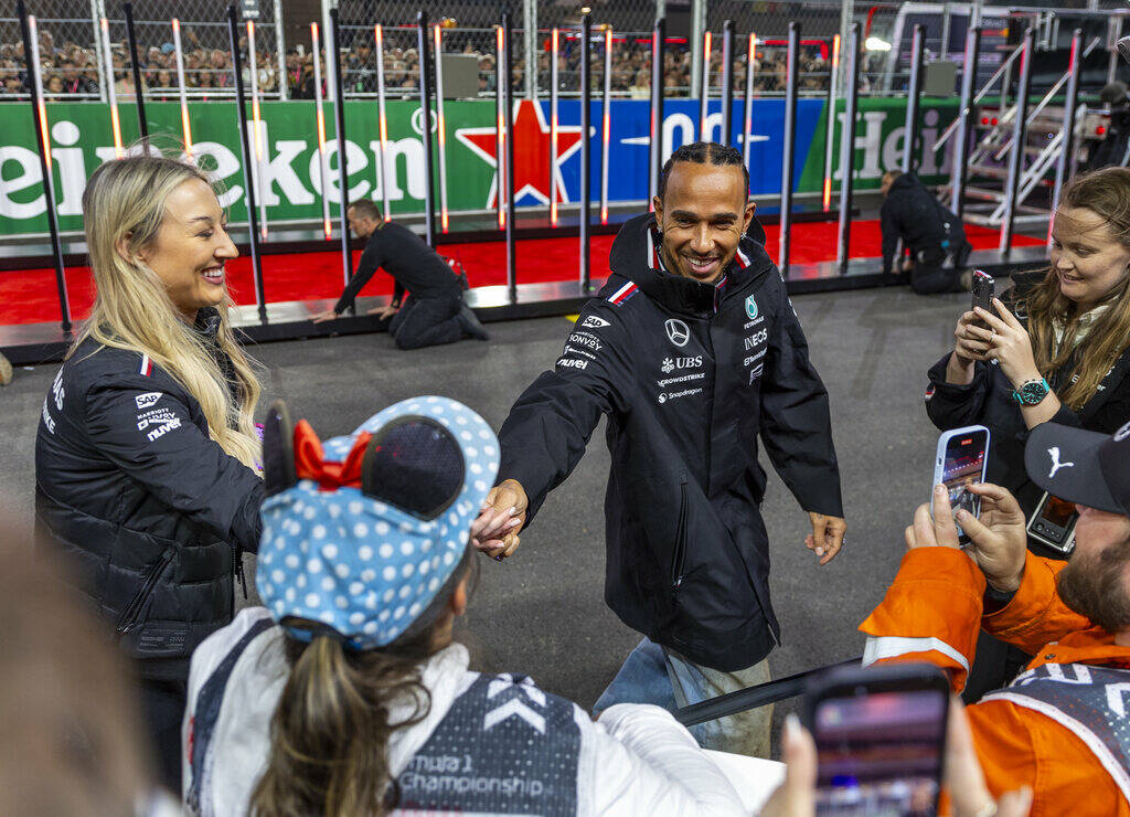 Mercedes driver Lewis Hamilton signs an autograph for a fan on the track after he's introduced ...