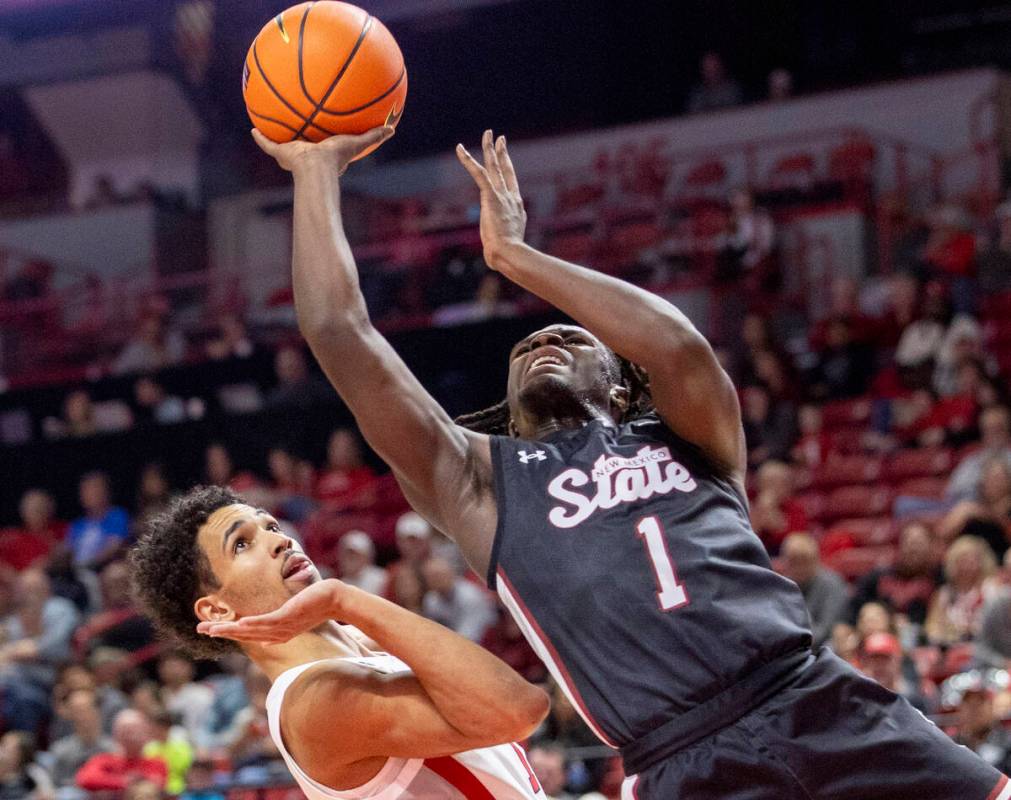 UNLV guard Jailen Bedford, left, avoids touching New Mexico State Aggies guard Gabe Pickens (1) ...