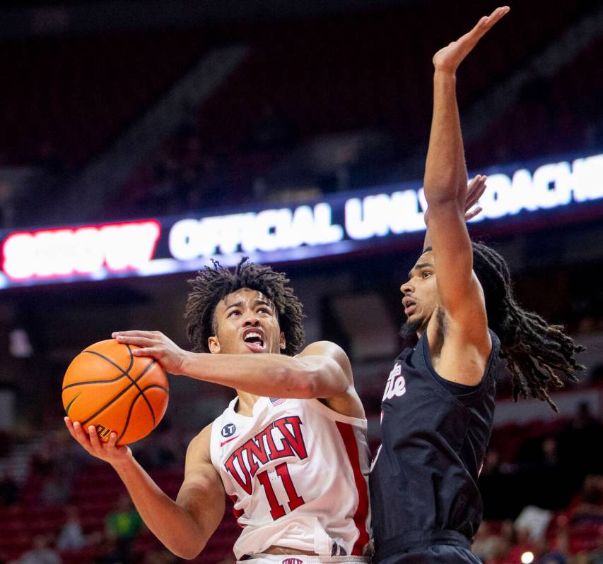 UNLV guard Dedan Thomas Jr. (11) attempts to shoot a layup past New Mexico State Aggies guard C ...