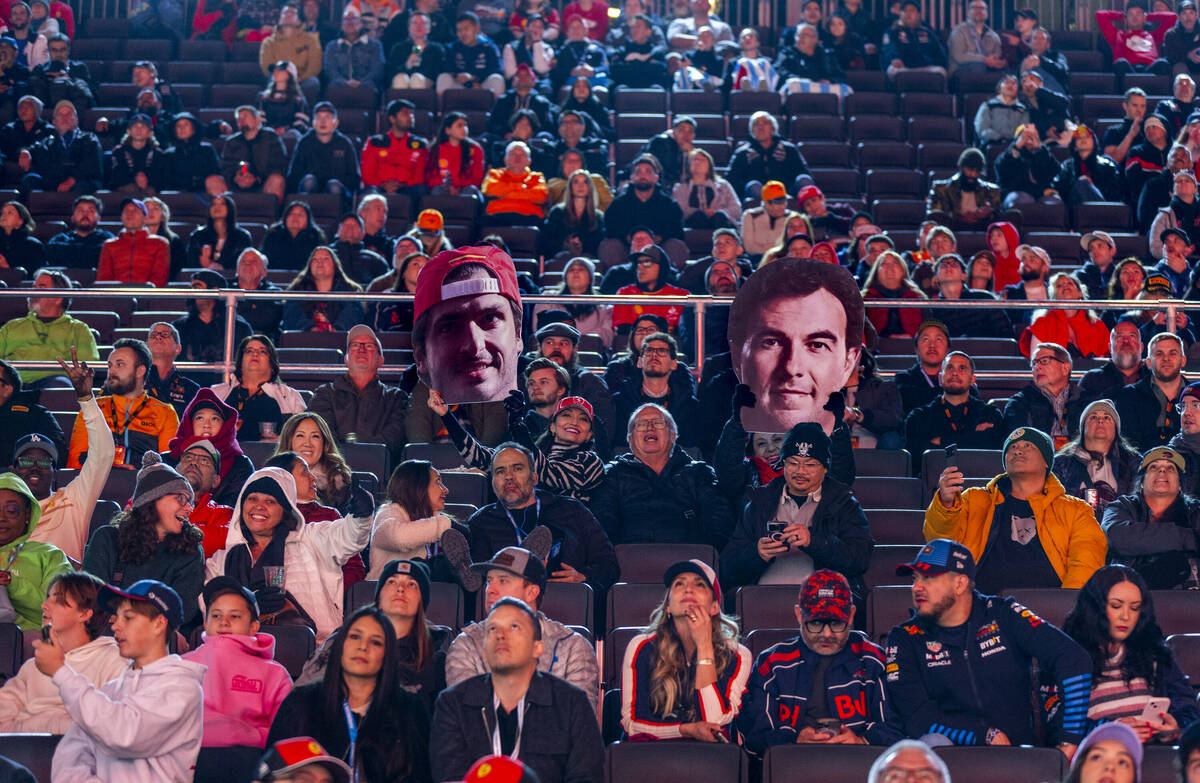 Fans hold up cutouts of Ferrari driver Carlos Sainz and Red Bull Racing driver Sergio Perez dur ...