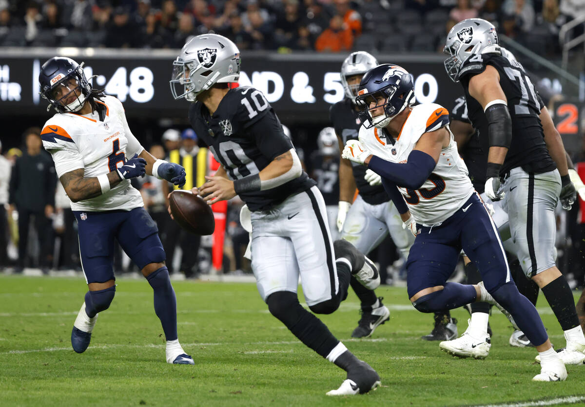 Raiders quarterback Desmond Ridder (10) is chased by Denver Broncos safety P.J. Locke (6) and l ...