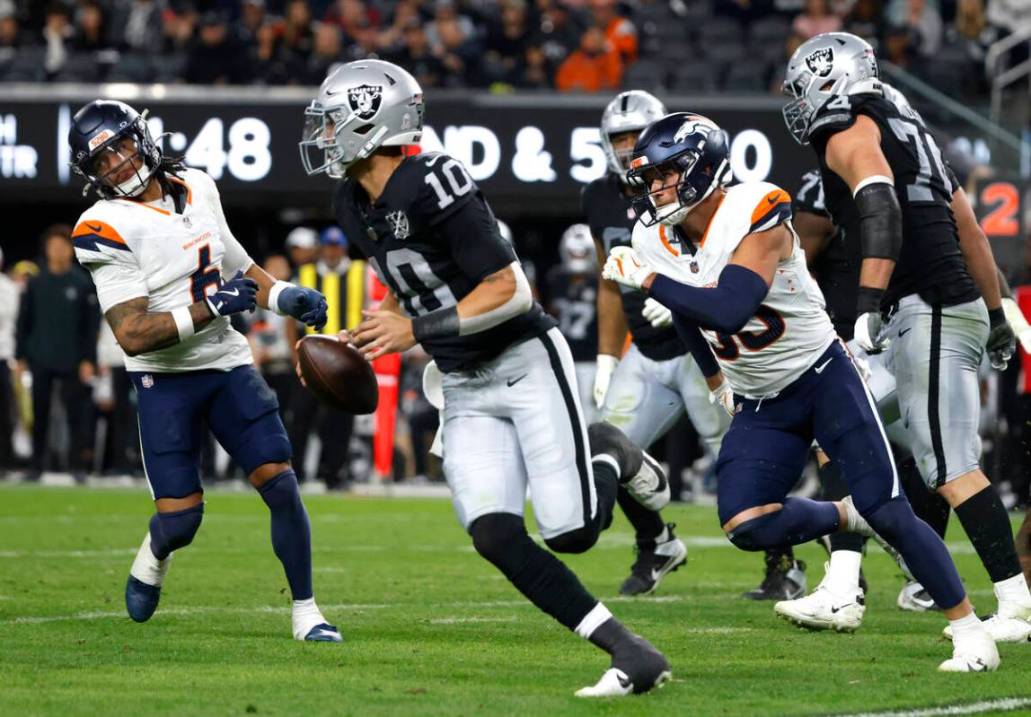 Raiders quarterback Desmond Ridder (10) is chased by Denver Broncos safety P.J. Locke (6) and l ...