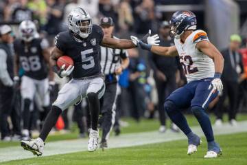 Raiders linebacker Divine Deablo (5) looks to escape a tackle by Denver Broncos linebacker Jona ...