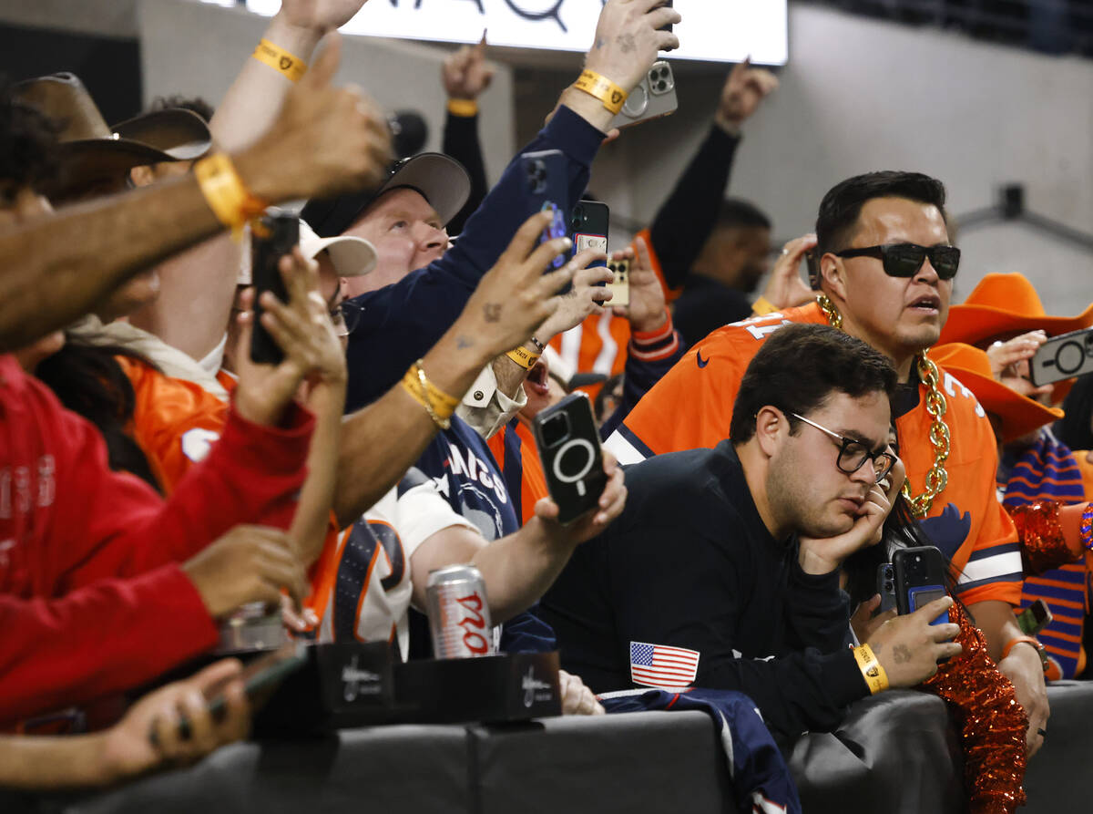 Denver Broncos fans celebrate as their team scored a touchdown as a Raiders fan, right, looks d ...