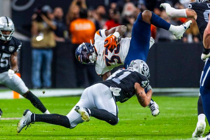 Raiders linebacker Robert Spillane (41) upends Denver Broncos running back Javonte Williams (33 ...