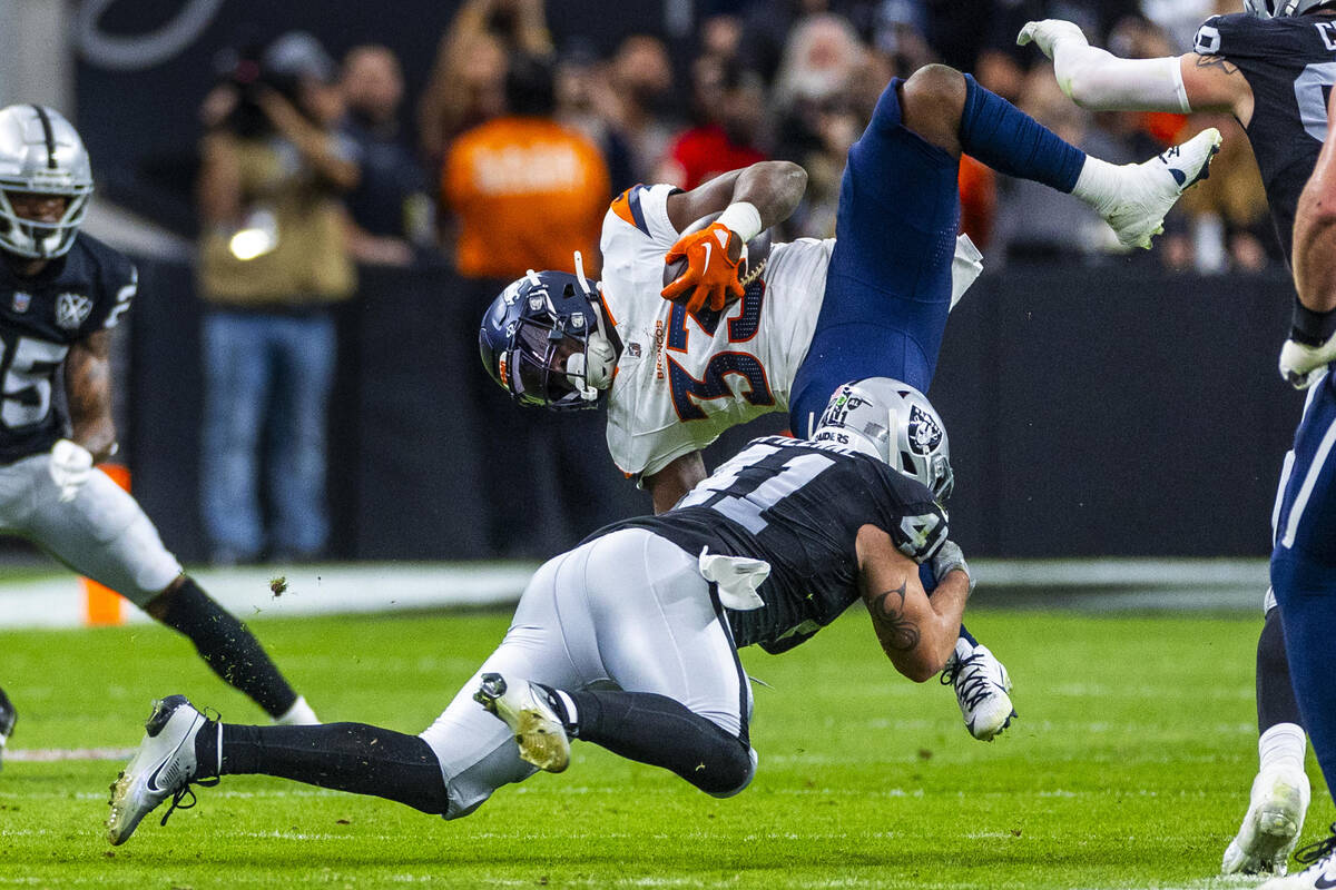 Raiders linebacker Robert Spillane (41) upends Denver Broncos running back Javonte Williams (33 ...