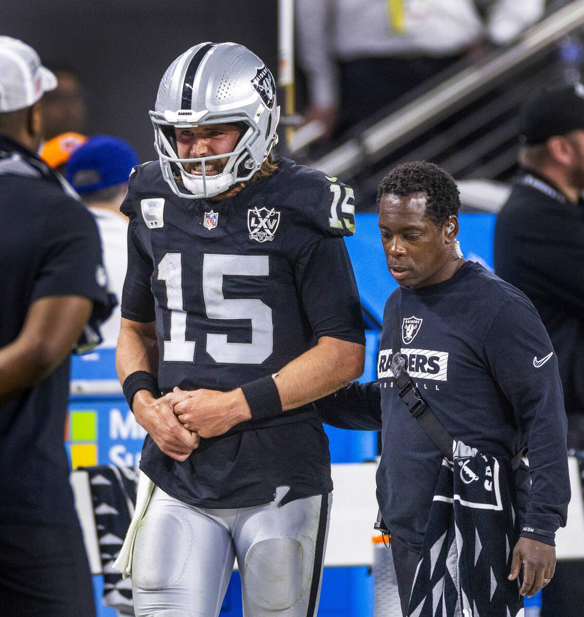 Raiders quarterback Gardner Minshew (15) is escorted off the field after a sack with a hand inj ...