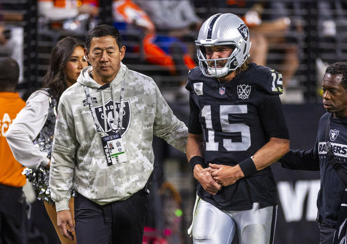 Raiders quarterback Gardner Minshew (15) is escorted off the field by team orthopedic surgeon D ...