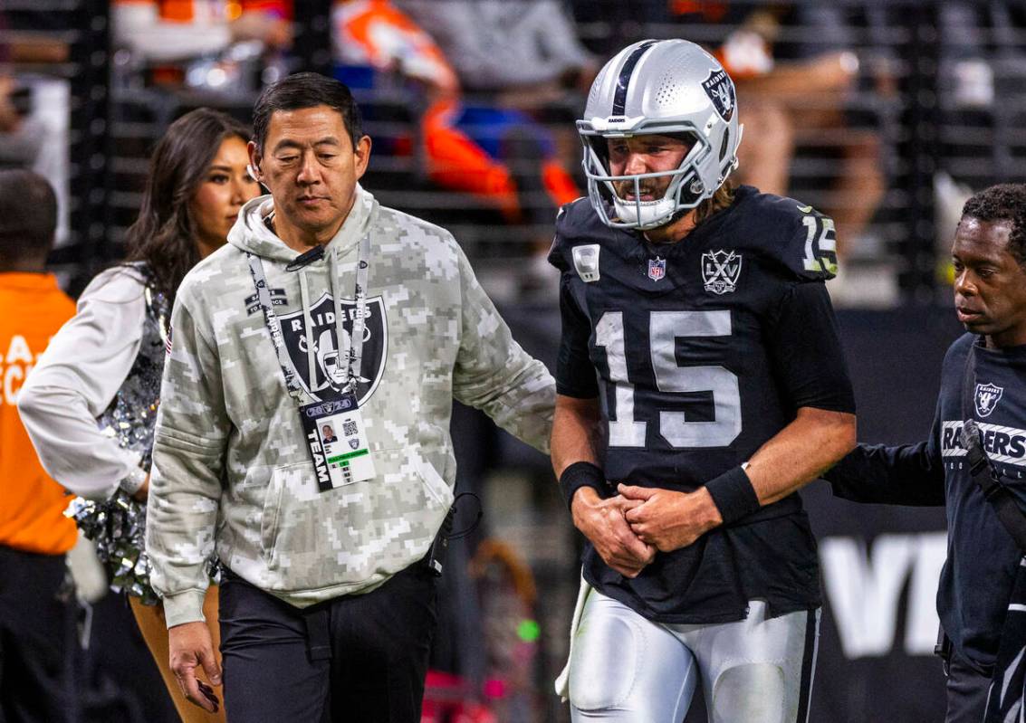 Raiders quarterback Gardner Minshew (15) is escorted off the field by team orthopedic surgeon D ...