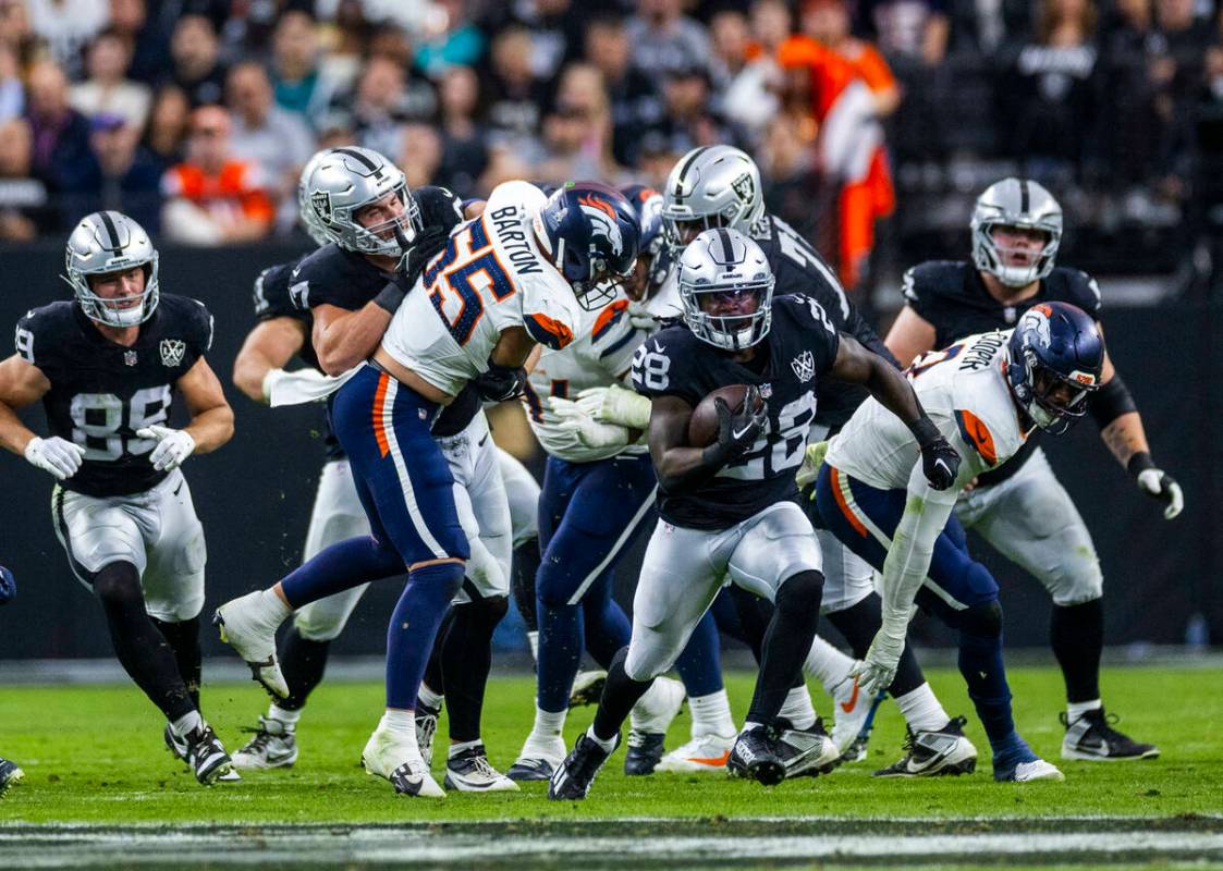 Raiders running back Sincere McCormick (28) break through the line and up the field as Denver B ...